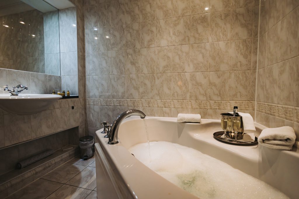 A romantic hotel bathroom offering a jacuzzi bath and a sleek sink for a St Valentine's getaway.