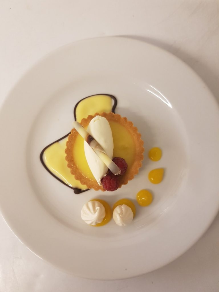 A Mother's Day dessert on a white plate with yellow and white icing, a sweet treat to celebrate.